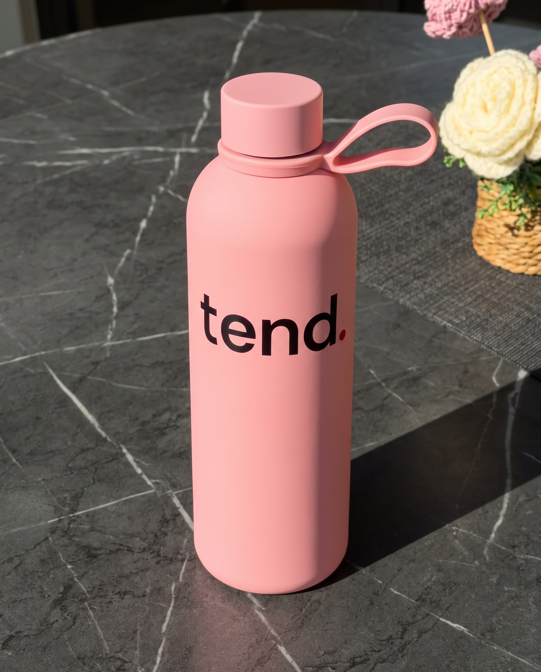 The pink tend. water bottle on a grey marble table in morning sun